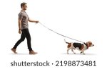 Small photo of Full length profile shot of a cool young man walking a basset hound dog on a lead isolated on white background