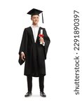 Small photo of Full length portrait of a smiling male student wearing a graduation gown and holding a diploma isolated on white background