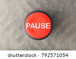 Overhead of a red pause push button over a blurred gray background