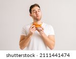 Small photo of Portrait of handome young man with enjoying eating delicious slice of pizza, with closed eyes from pleasure on white isolated background. Studio shot of hungry male student eating tasty food.