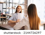 Small photo of Rear view of unrecognizable young woman employers being interviewed for job in design company, having conversations about successful startup, sitting at desk opposite each other.