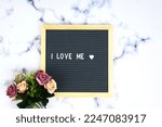 Small photo of Letter board with phrase I love me white background, flowers with heart. Concept of mental health. Aspiration, supportive sentence, law of attractions, affirmatives, subconscious mind, NLP.