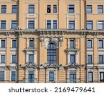 Vintage architecture classical facade with large arch window and stucco decorations. Front view.