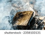 Small photo of A camp fire smolders and smokes about ready to ignite. The think smoke rolls over the burnt wood. campfire, fire, wood, firepit, smoldering, smoking, smokey, burning, camping, rolling