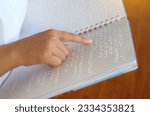 Visually impaired person reads with his fingers a book written in braille It is written for those who are visually impaired or blind. It is a special code generated from 6 dots in the box.            