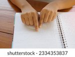 Small photo of Visually impaired person reads with his fingers a book written in braille It is written for those who are visually impaired or blind. It is a special code generated from 6 dots in the box.