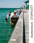 Small photo of MELBOURNE/AUSTRALIA - FEBRUARY 6: Youths jump off a jetty into the water, while others fish in Mordialloc, a coastal suburb of Melbourne, Australia in February.