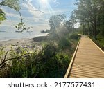 Beautiful wooden path besides sand coast and sea. Sunny blue sky. 