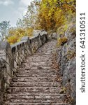 Small photo of Beautiful upgoing old stone stairway among brown autumn leaves