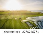 Small photo of Windmills and solar panels farm in green fields close to the ocean. Renewable energies concept. Green energy for carbon dioxide emission reduction.