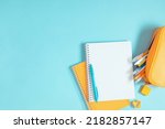 Back to school background. Flat lay, top view of colorful scattered stationery on isolated pastel blue table background. School supplies on desk. Copyspace.