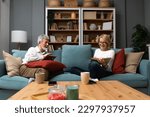 Small photo of Simple living. Happy middle-aged senior couple 70s husband and wife sit relax on couch in living room reading book drinking tea together, calm elderly 60s couple booklovers rest at home enjoy life