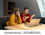 Small photo of Two young freelance business women teamwork working at home on laptop as product strategy expert. Female expatriate remote work on internet on computer online for foreign company as web developer.