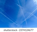 Airplanes leaving diagonal contrails on a clear blue sky