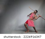 Small photo of masai warrior about to throw his spear furiously.Grey mockup space.Huge blank background space.Copy text and paste