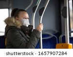 Coronavirus, covid 2019, young woman with respiratory mask traveling in the public transport by bus