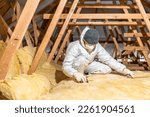 man insulates the roof and ceiling of the house with glass wool