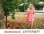 Little girl walks in the garden. Back view