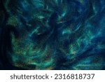 Small photo of Various stains and overflows of gold particles in blue fluid with green tints. Golden particles dust and smooth defocused background. Liquid iridescent shiny backdrop with depth of field.