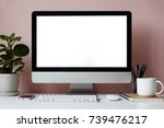 Mock up of white desktop with electronic devices, stationary items, cup of tea, copybook and decorative green plant over pinkish wall. Minimalistic modern workplace of student or freelancer
