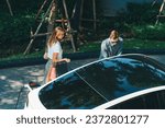 Small photo of Young couple travel with EV electric car charging in green sustainable city outdoor garden in summer shows urban sustainability lifestyle by green clean rechargeable energy of electric vehicle innards