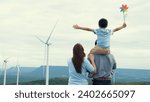 Small photo of Concept of progressive happy family enjoying their time at the wind turbine farm. Electric generator from wind by wind turbine generator on the country side with hill and mountain on the horizon.
