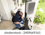 Small photo of Qualified technician install home EV charging station, providing maintenance service for electric vehicle's battery charging platform at home. EV car technology for residential utilization. Synchronos