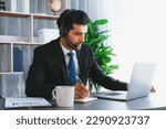 Small photo of Male call center operator or telesales representative siting at his office desk wearing headset and engaged in conversation with client providing customer service support or making a sale. fervent