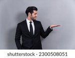 Confident businessman in formal suit making holding hand gesture to indicate promotion or advertising on empty space with excited facial expression and gesture on isolated background. Fervent