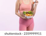 Small photo of Young sporty Asian woman in sportswear holding salad bowl fill with vibrant of fruit and vegetable. Natural youthful and fit body lifestyle with balance nutrition on isolated background. Vigorous