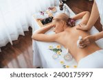 Small photo of Hot herbal ball spa massage body treatment, masseur gently compresses herb bag on woman body. Tranquil and serenity of aromatherapy recreation in day lighting ambient at spa salon. Quiescent