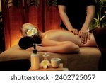 Small photo of Caucasian woman customer enjoying relaxing anti-stress spa massage and pampering with beauty skin recreation leisure in warm candle lighting ambient salon spa at luxury resort or hotel. Quiescent