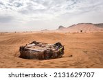Small photo of Burnt abandoned car in the sands. Scary post apocalyptic scene