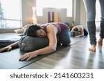 Small photo of Woman using bolster in restorative yoga childs pose
