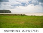 Small photo of Baltic sea beach landscape, coast at the island of Ruegen in Germany, storm and rain over the brack water, high waves and green grass