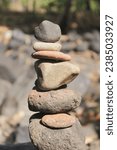 Small photo of Pile of Balanced Stones Cairn - Smooth stones stacked into a cairn along the edge of a body of water symbolize balance and harmony. MyRealHoliday, My Real Holiday