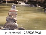 Small photo of Pile of Balanced Stones Cairn - Smooth stones stacked into a cairn along the edge of a body of water symbolize balance and harmony. MyRealHoliday, My Real Holiday