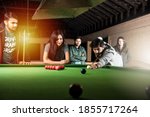 A group of young Indian asian young people or friends playing fun billiards, snooker or pool