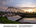steel bridge over a river at sunset. countryside scenery. sunset by the river. rustic steel bridge over a calm river.