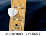 Small photo of the neck from an electric guitar. between the strings is a plectron