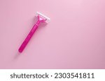 Disposable shaving razor for hair removal on pink background