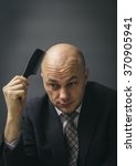 Small photo of Bald businessman combing his nonexistent hair