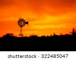 Silhouette of a windmill in front of a bright orange sunset.