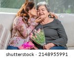 Small photo of Happy Mother's Day! Hispanic mom and daughter kiss, hug and give each other flowers and gifts on a special day.