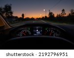 Driver view to the speedometer at 59 kmh or 59 mph, on a road blurred in motion, night fall view from inside a car of driver POV of the road landscape.