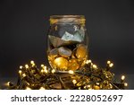 Glass jar with euro coins and paper boat centered on a dark background on top of led lights. Euro pocket savings coin concept.