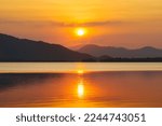 Silhouette, beautiful landscape with sunset at coast of the lake in summer. Nature landscape. reflection, orange sky and yellow sunlight, romantic. Amazing scene at lake in Huai Mai Teng, Thailand