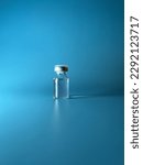 Small photo of Transparent ampoule on a blue background. Contains medical supplies, drug, liquid or vaccine. One vial for medicine, aesthetic medicine treatment. Verticale