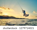                      Young man kite boarder jumps over the sea at sunset           