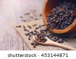 dried cloves on wooden spoon and  background.